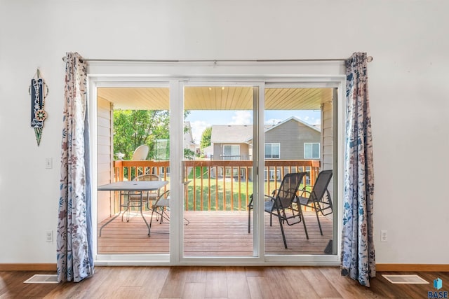 doorway to outside with baseboards, visible vents, and wood finished floors