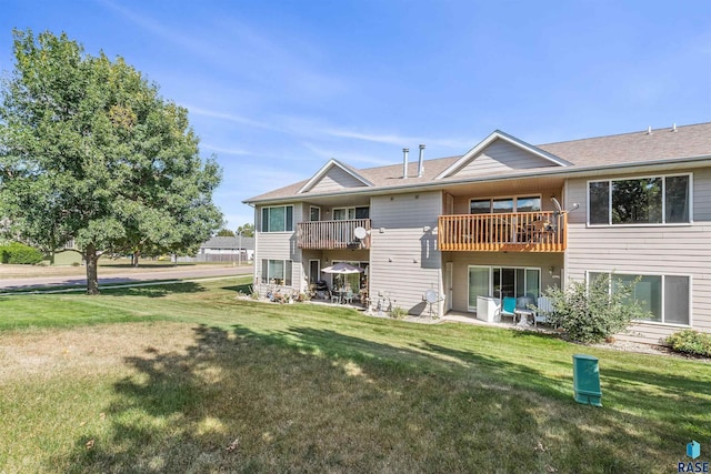 rear view of house with a balcony and a lawn