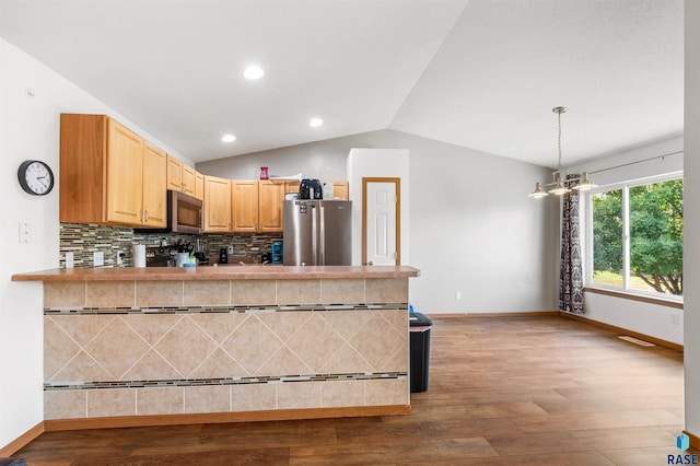 kitchen with dark wood finished floors, decorative backsplash, appliances with stainless steel finishes, vaulted ceiling, and a peninsula