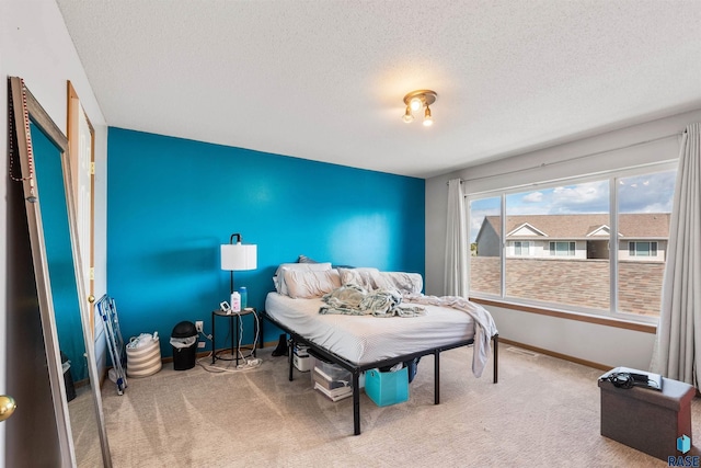 carpeted bedroom featuring visible vents, a textured ceiling, and baseboards