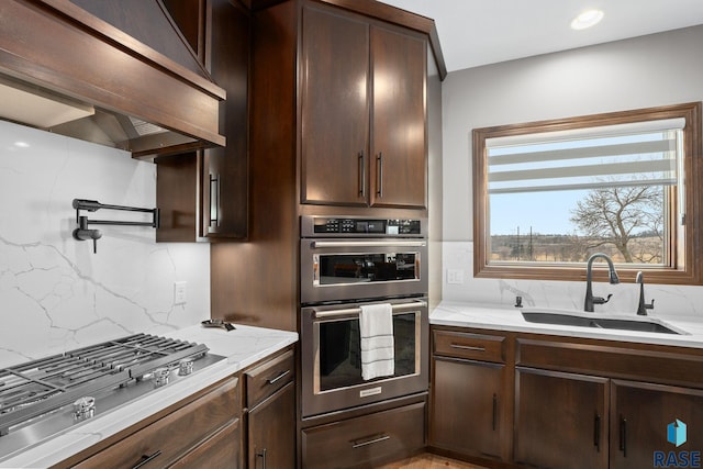 8501 E Torchwood Pl, Sioux Falls, SD 57110 - kitchen featuring range hood, stainless steel appliances, backsplash, a sink, and dark brown cabinetry
