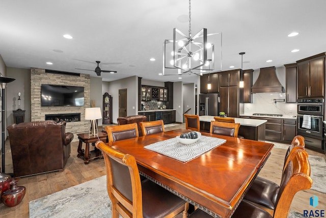 8501 E Torchwood Pl, Sioux Falls, SD 57110 - dining area with ceiling fan with notable chandelier, a fireplace, light wood-style flooring, and recessed lighting