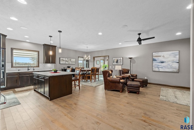 8501 E Torchwood Pl, Sioux Falls, SD 57110 - kitchen featuring dark brown cabinetry, light wood-style floors, light countertops, and a center island