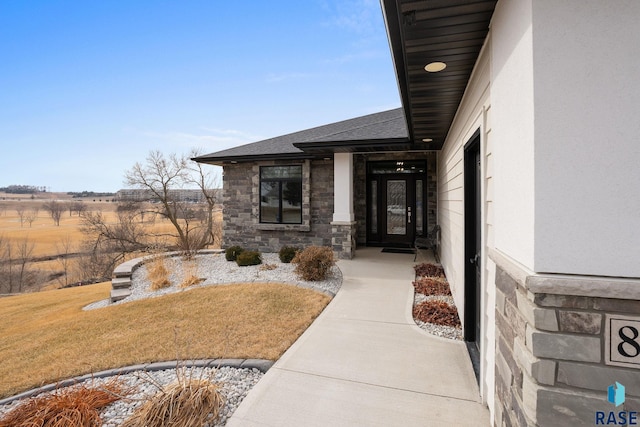 8501 E Torchwood Pl, Sioux Falls, SD 57110 - property entrance with stone siding, roof with shingles, a lawn, and stucco siding