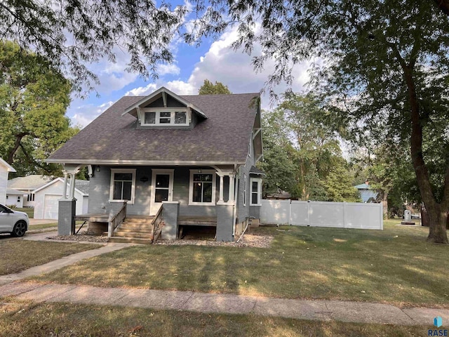 bungalow-style home with a porch, a front yard, roof with shingles, and fence