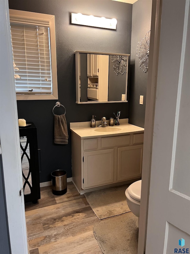 bathroom with toilet, baseboards, wood finished floors, and vanity