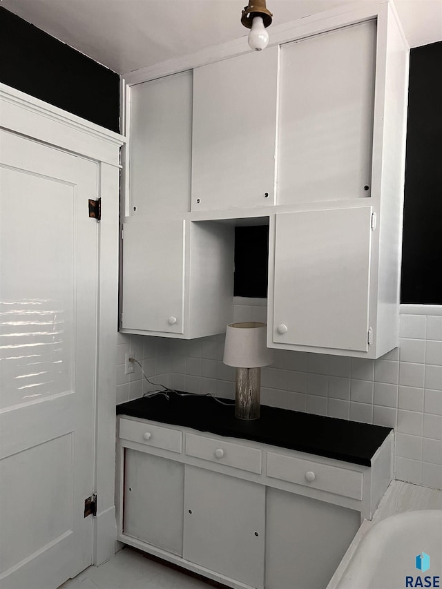 kitchen with dark countertops, white cabinets, and backsplash