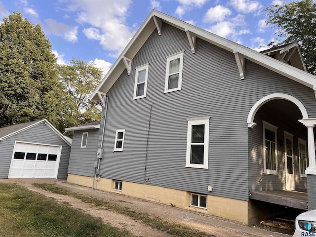 view of home's exterior with a garage, driveway, and an outbuilding