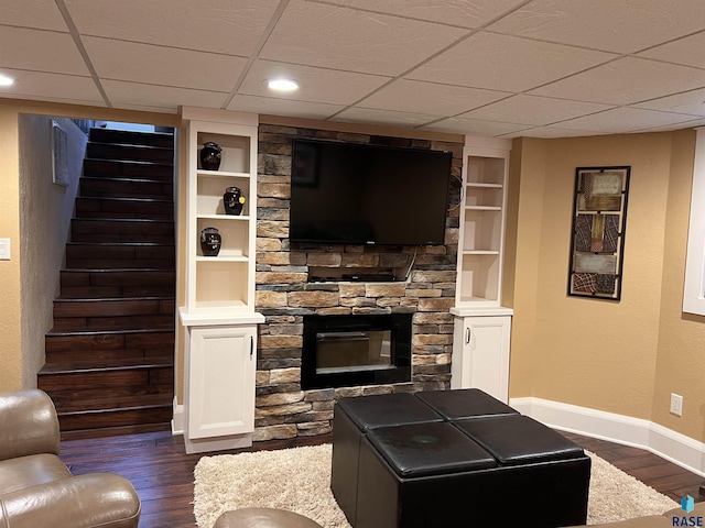 living room with dark wood-style floors, built in shelves, a fireplace, baseboards, and stairs