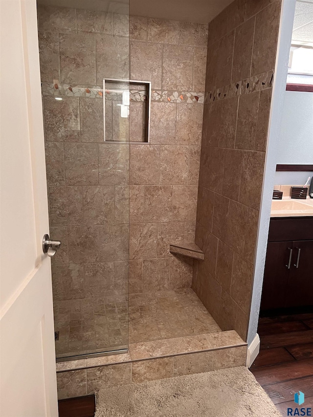 bathroom with vanity, tiled shower, and wood finished floors