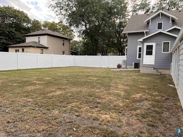 view of yard with entry steps, central air condition unit, and a fenced backyard