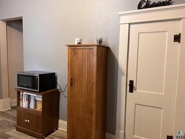 interior space featuring stainless steel microwave, wood finished floors, and baseboards