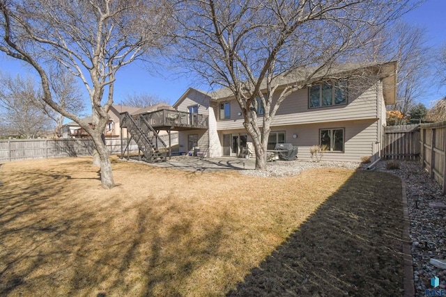 back of property with a wooden deck, a fenced backyard, stairway, a yard, and a patio area