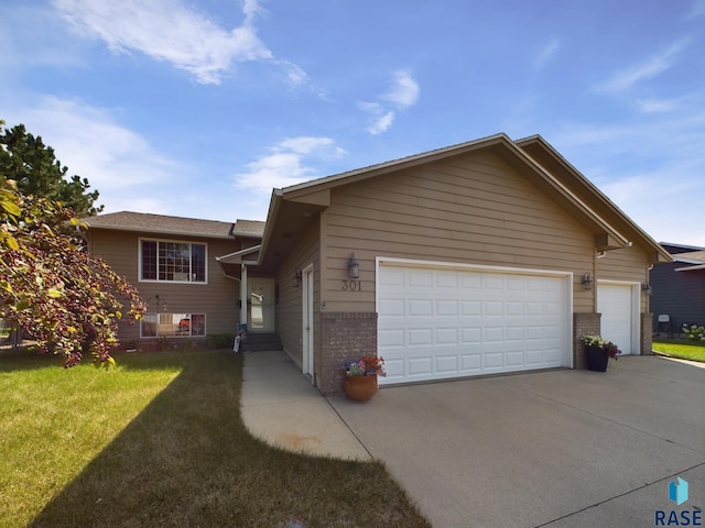 view of front of property featuring an attached garage, driveway, a front lawn, and brick siding