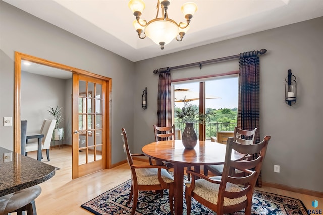 dining area with a healthy amount of sunlight, light wood-style floors, baseboards, and a chandelier