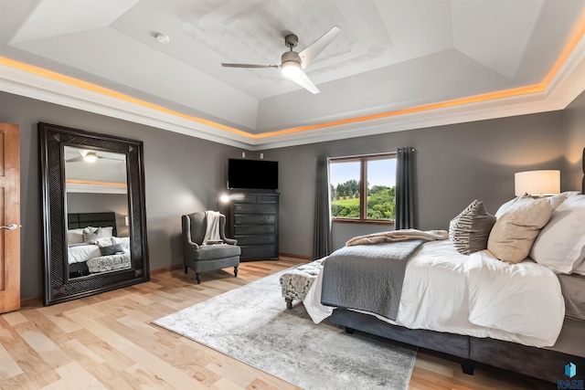 bedroom featuring light wood-style flooring, a tray ceiling, and a ceiling fan