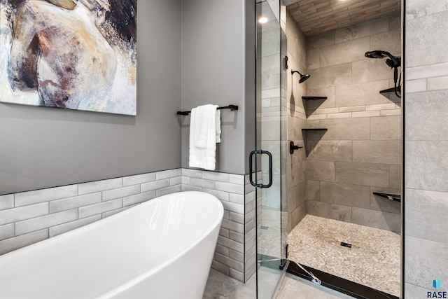 full bath with a stall shower, a freestanding tub, tile walls, and wainscoting