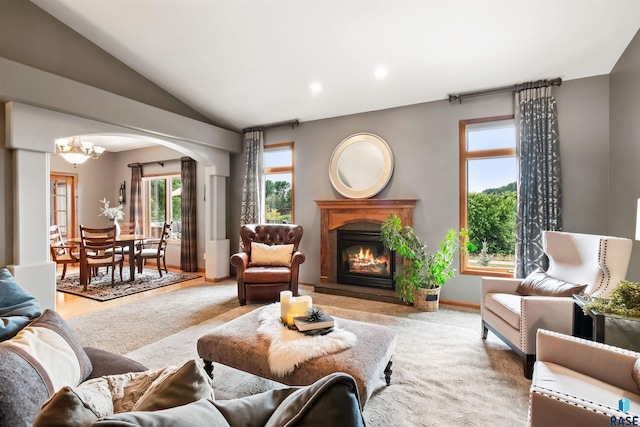 living room featuring arched walkways, recessed lighting, an inviting chandelier, a glass covered fireplace, and vaulted ceiling