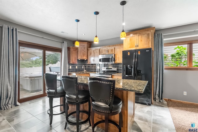 kitchen featuring dark stone counters, a kitchen island, a breakfast bar, stainless steel appliances, and backsplash