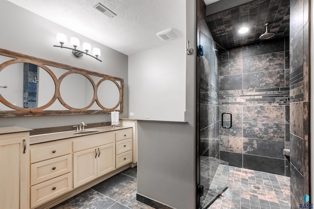 full bathroom with a textured ceiling, vanity, a shower stall, and visible vents