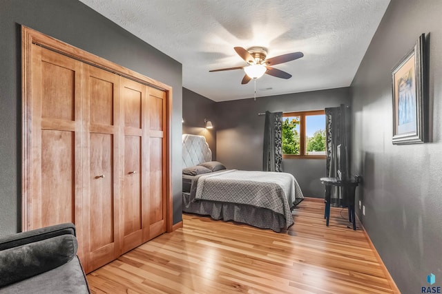 bedroom featuring a textured ceiling, a ceiling fan, light wood-style flooring, and baseboards