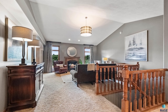 living room with light carpet, a glass covered fireplace, and lofted ceiling