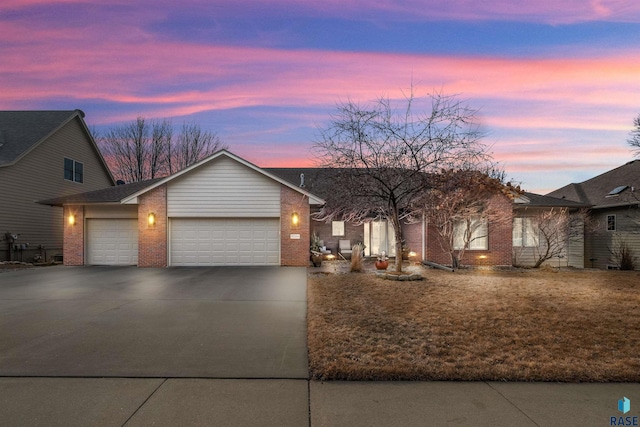 view of front of house featuring concrete driveway, brick siding, a front lawn, and an attached garage