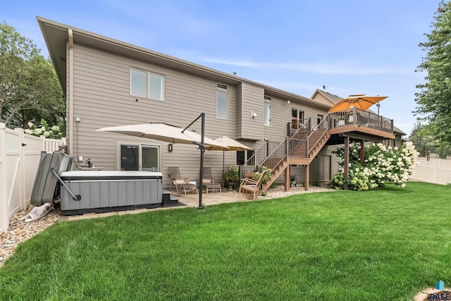 back of house featuring a patio area, a hot tub, a lawn, and a fenced backyard