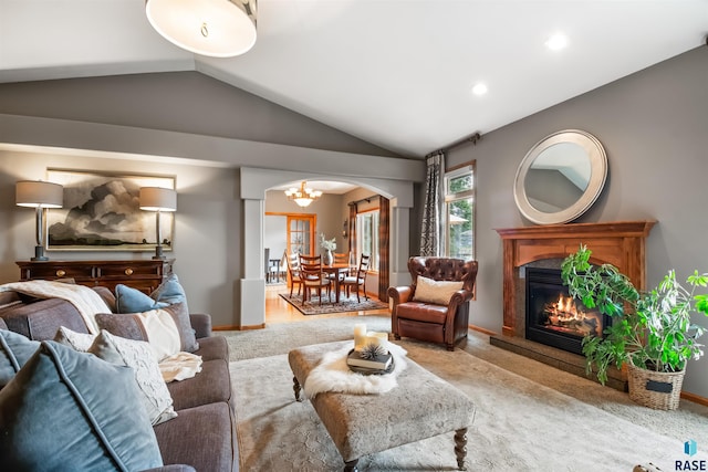 living area featuring light carpet, arched walkways, lofted ceiling, a premium fireplace, and a notable chandelier