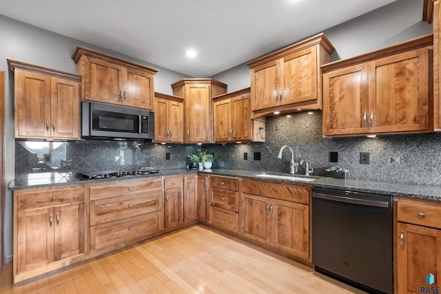 kitchen with dishwasher, stainless steel microwave, a sink, and brown cabinets