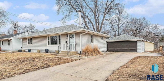 single story home with a garage, an outbuilding, central AC, and a shingled roof