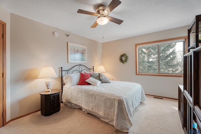 carpeted bedroom with a ceiling fan, visible vents, a textured ceiling, and baseboards