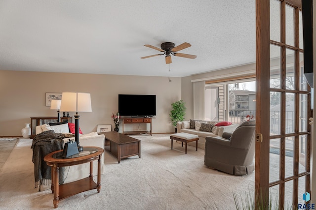 living room with light colored carpet, ceiling fan, a textured ceiling, and baseboards