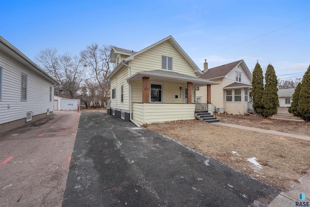 view of front of house featuring driveway, covered porch, and an outdoor structure