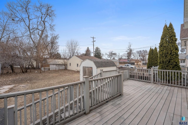 wooden terrace featuring a storage shed, fence, and an outdoor structure