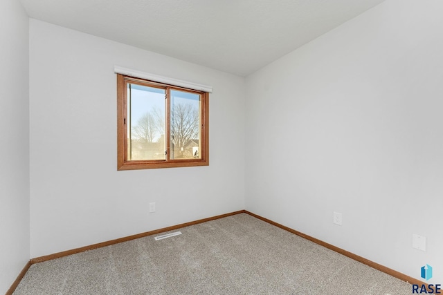 carpeted spare room featuring visible vents and baseboards