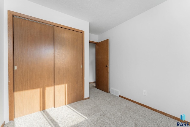 unfurnished bedroom with baseboards, carpet, visible vents, and a closet