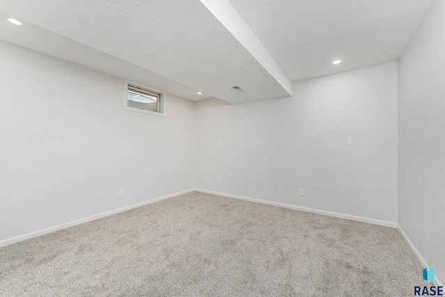 below grade area featuring recessed lighting, visible vents, carpet flooring, a textured ceiling, and baseboards