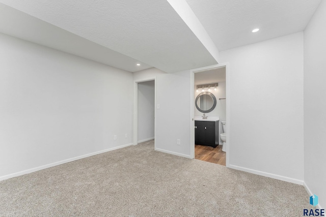 unfurnished bedroom with carpet, recessed lighting, connected bathroom, a textured ceiling, and baseboards