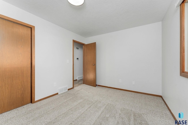 unfurnished bedroom featuring baseboards, a textured ceiling, visible vents, and carpet flooring