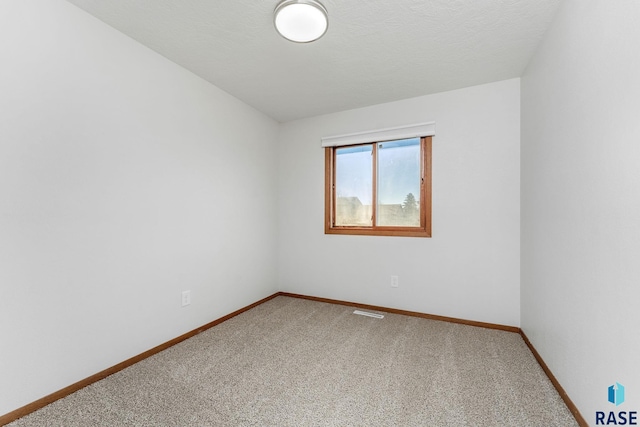 carpeted empty room featuring visible vents, a textured ceiling, and baseboards