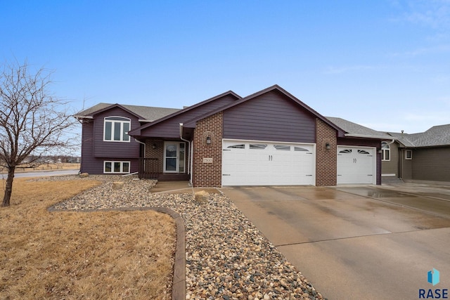 split level home featuring concrete driveway, brick siding, and an attached garage