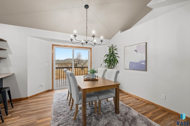 dining space with lofted ceiling, baseboards, a chandelier, and light wood-style floors