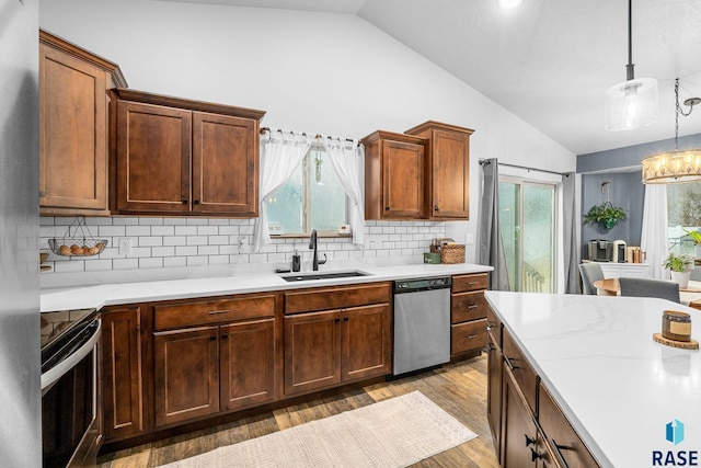 kitchen featuring stainless steel appliances, lofted ceiling, light countertops, and a sink