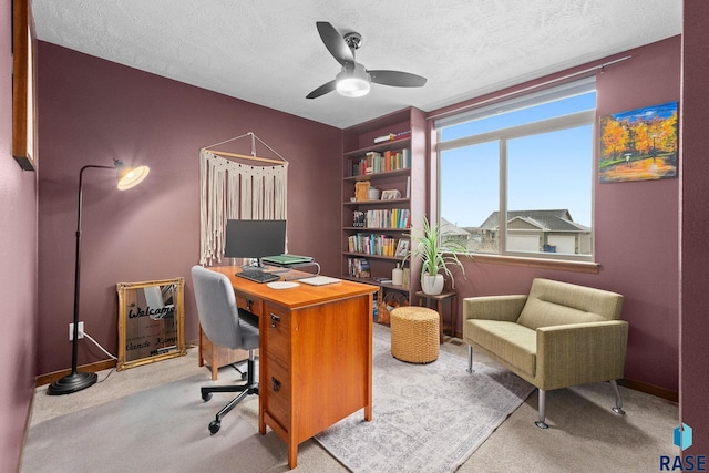 carpeted home office with a textured ceiling, baseboards, a ceiling fan, and built in features