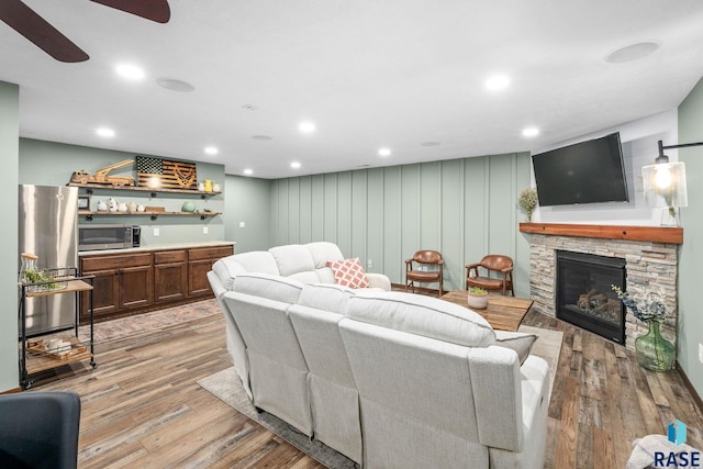 living area with ceiling fan, light wood-style flooring, recessed lighting, a fireplace, and wet bar