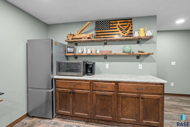 kitchen with baseboards, appliances with stainless steel finishes, wood finished floors, light countertops, and open shelves