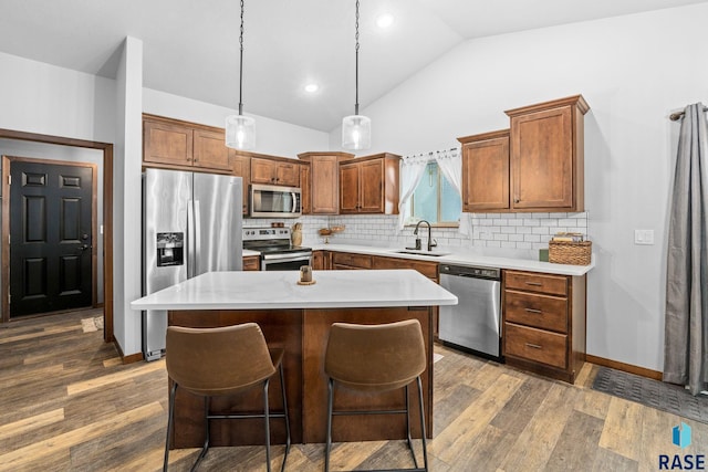 kitchen featuring a sink, a center island, appliances with stainless steel finishes, decorative backsplash, and dark wood finished floors