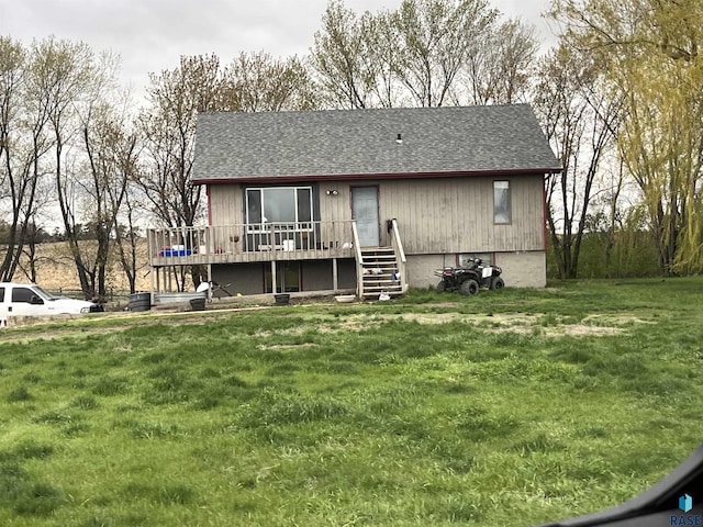 view of front of home with a deck, a front lawn, and roof with shingles