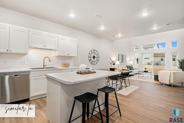 kitchen with a sink, light wood-type flooring, open floor plan, and stainless steel dishwasher